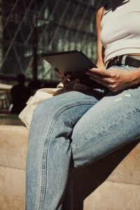 a woman sitting on a wall using a tablet